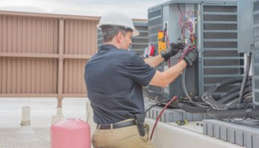 Technician checking for power on a rooftop condensing unit.